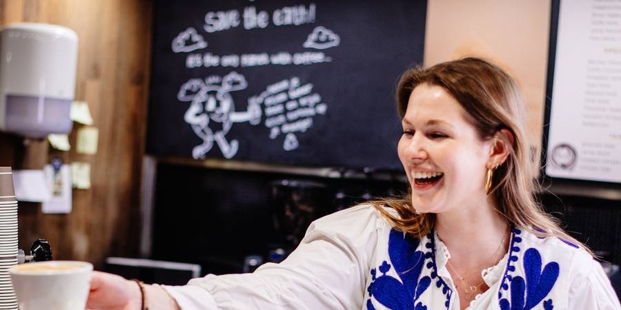 Smiling barista handing over a cup of coffee